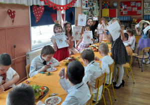 Grupa dzieci 5-6 letnich konsumujących słodki poczęstunek , dziewczyny z dyplomami Super Dziewczynki